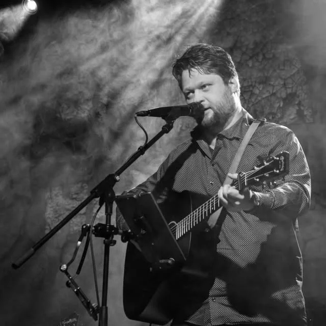 Hendrik Thiel auf der Bühne mit Gitarre und Mikrofon